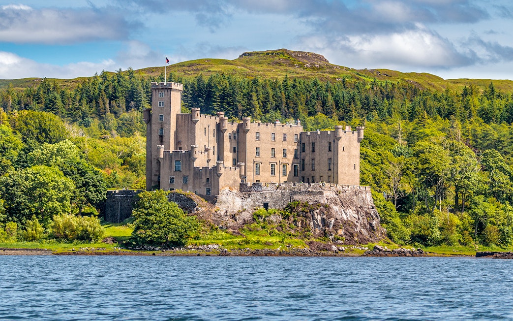 Dunvegan Castle on the Isle of Skye, surrounded by lush greenery and water.