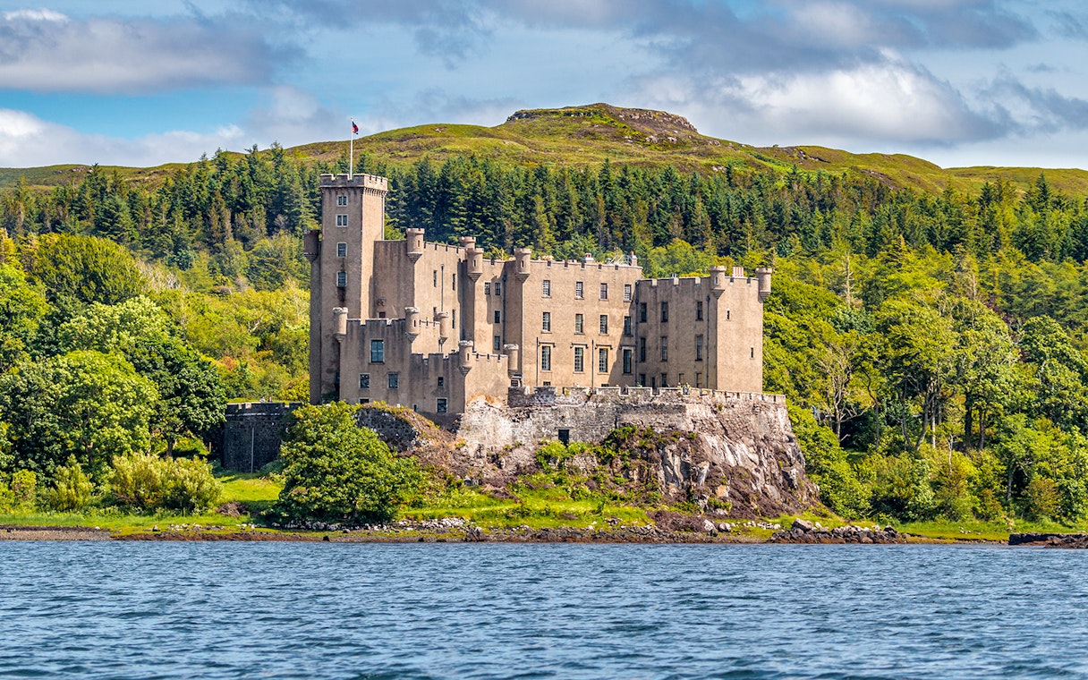 Dunvegan Castle on the Isle of Skye, surrounded by lush greenery and water.