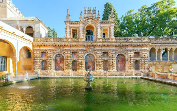 Alcazaba facade with ornate arches and central fountain, Alhambra Gardens, Spain.