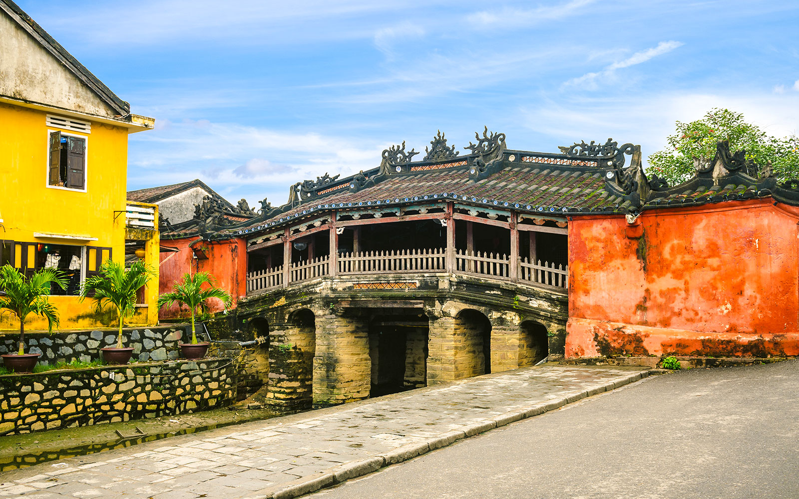 Japanese Covered Bridge in Hoi An, Vietnam, with vibrant yellow and red buildings nearby.
