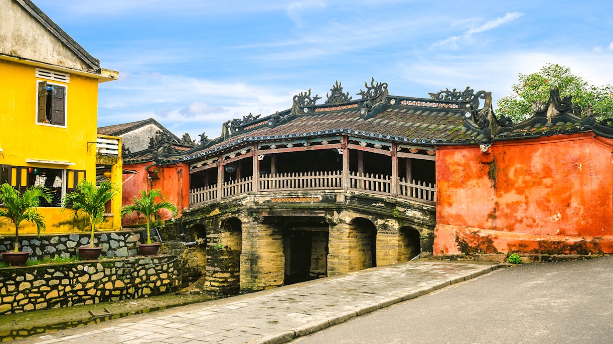 Japanese Covered Bridge in Hoi An, Vietnam, with vibrant yellow and red buildings nearby.