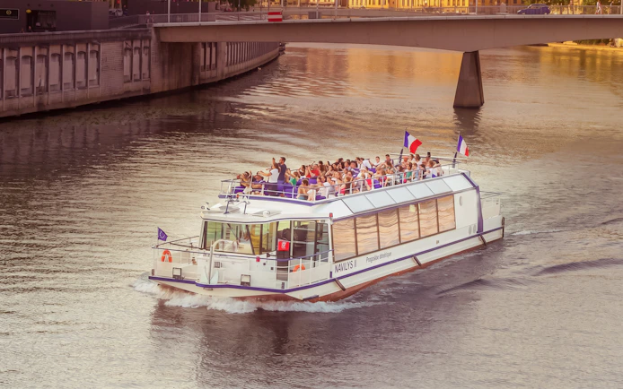 Tour boat cruising on the Saône River in Lyon with passengers enjoying the view.