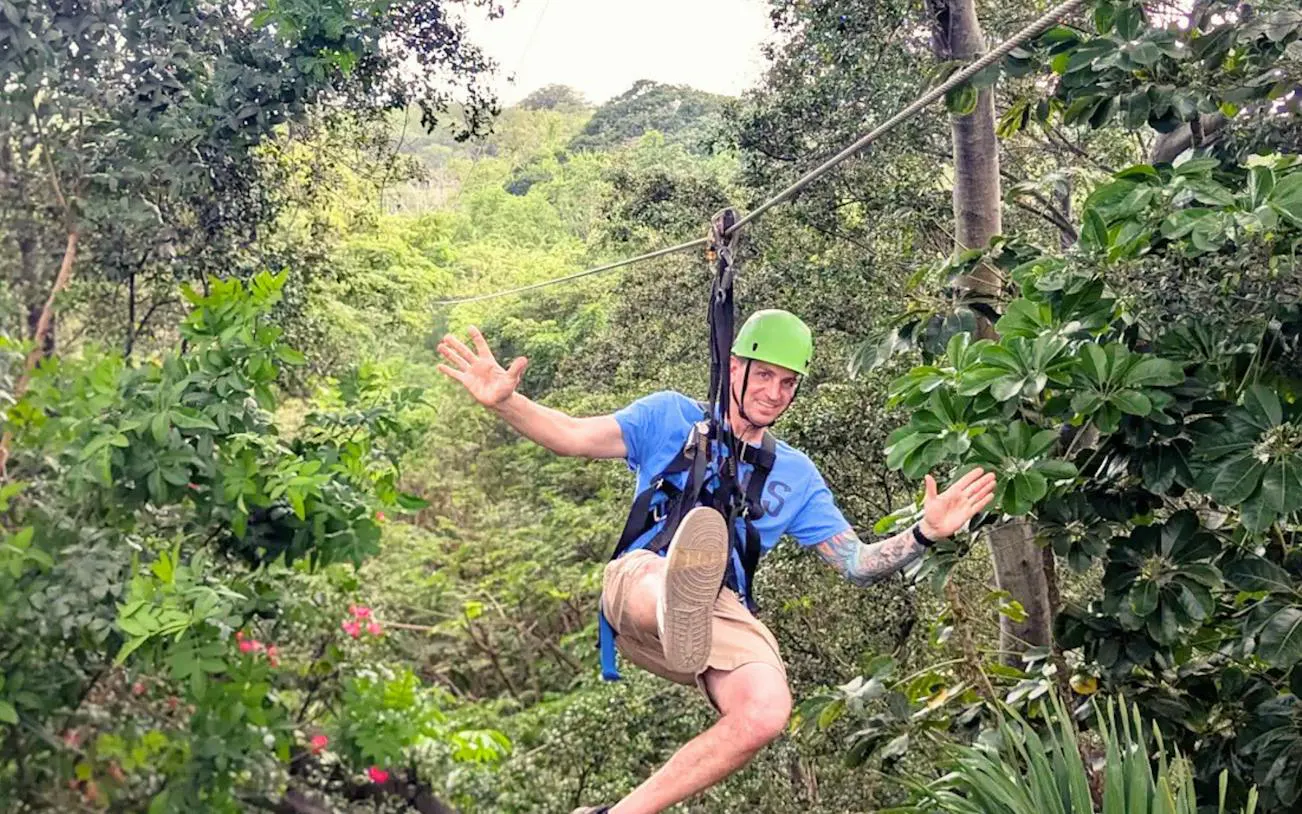 Person ziplining through lush forest in Oahu, part of Off-Road ATV and 3-Zipline Adventure Package.