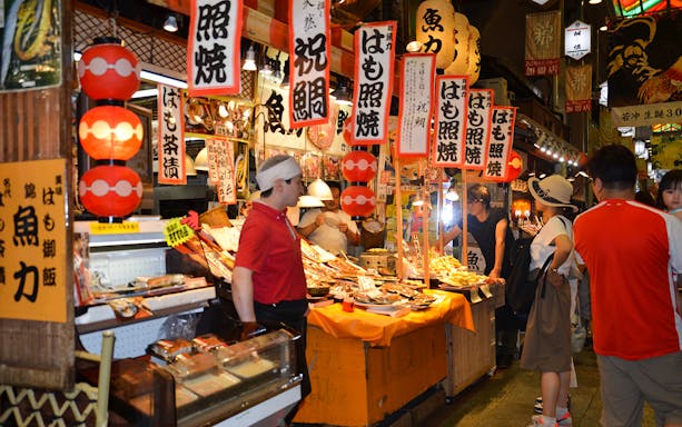 Kyoto Nishiki Market food stalls with visitors exploring local cuisine.