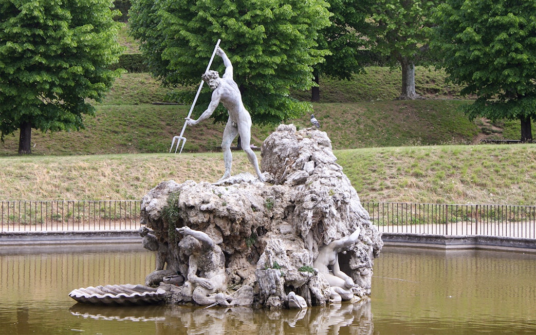 Fountain of Neptune statue in Boboli Gardens, Florence, surrounded by greenery.