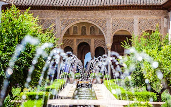 Courtyard with water channel and arches in Generalife Gardens, Alhambra, Granada.