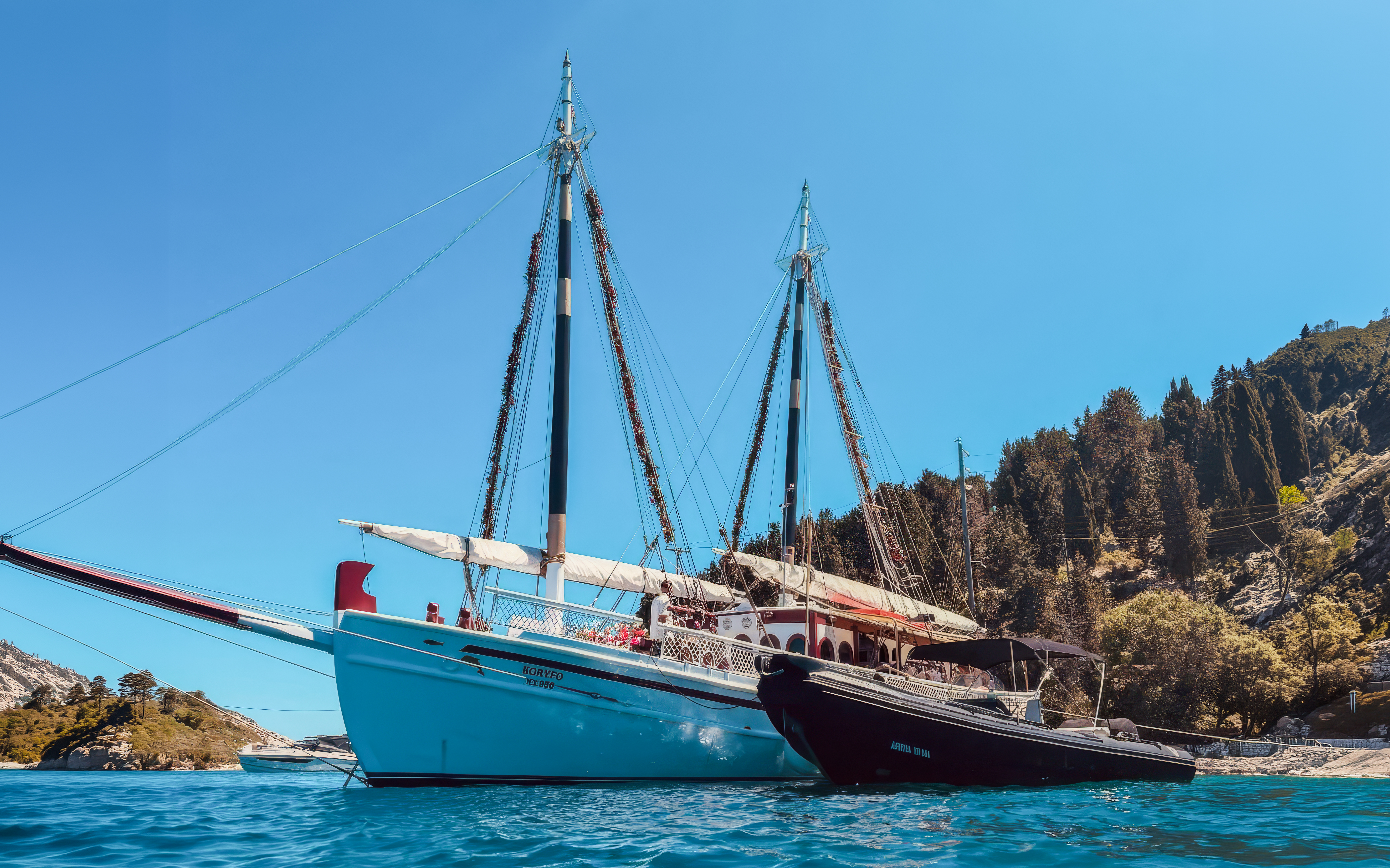 Sailing boats anchored near the coast of Corfu, Greece, with lush hills in the background.