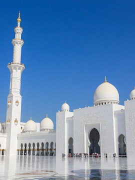 Sheikh Zayed Grand Mosque in Abu Dhabi with visitors exploring the courtyard.