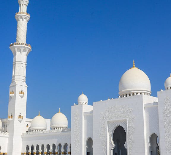 Sheikh Zayed Grand Mosque in Abu Dhabi with visitors exploring the courtyard.