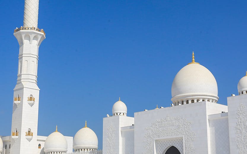 Sheikh Zayed Grand Mosque in Abu Dhabi with visitors exploring the courtyard.