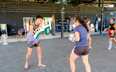 Beginners practicing Muay Thai boxing techniques in a Krabi gym class.