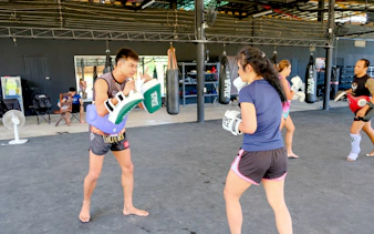 Beginners practicing Muay Thai boxing techniques in a Krabi gym class.