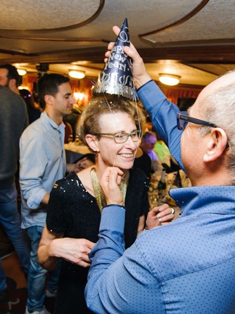 Guests celebrating on a New Year’s Eve cruise in Budapest with party hats and live music.