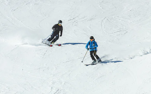 Skiers descending a snowy slope with Ultimate Starter Skiing Pass and equipment rentals.