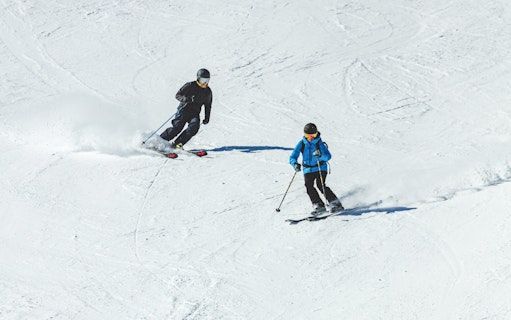 Skiers descending a snowy slope with Ultimate Starter Skiing Pass and equipment rentals.