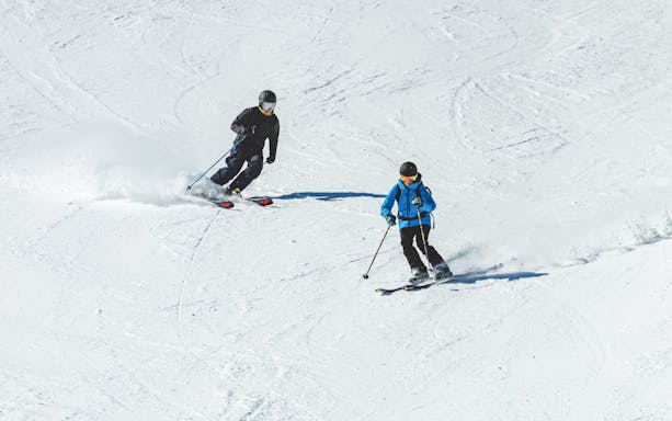 Skiers descending a snowy slope with Ultimate Starter Skiing Pass and equipment rentals.
