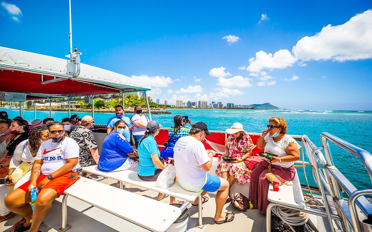Passengers on a boat enjoying views of the ocean and Waikiki coastline.