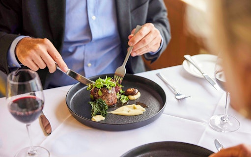 Tourist enjoying Australian beef cheek on evening cruise dining experience.