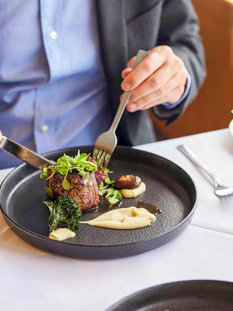 Tourist enjoying Australian beef cheek on evening cruise dining experience.