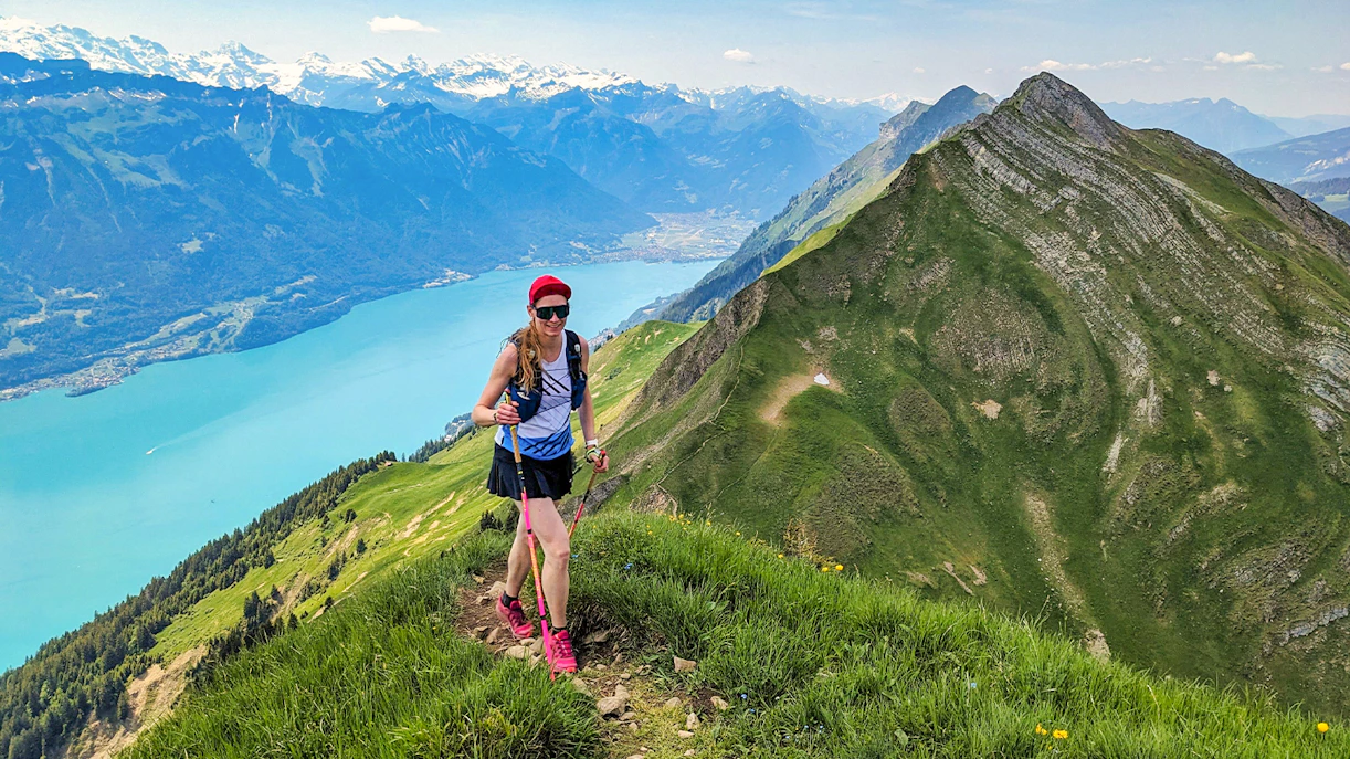 Hiker on Harder Kulm trail with view of Lake Thun and Swiss Alps in Interlaken.