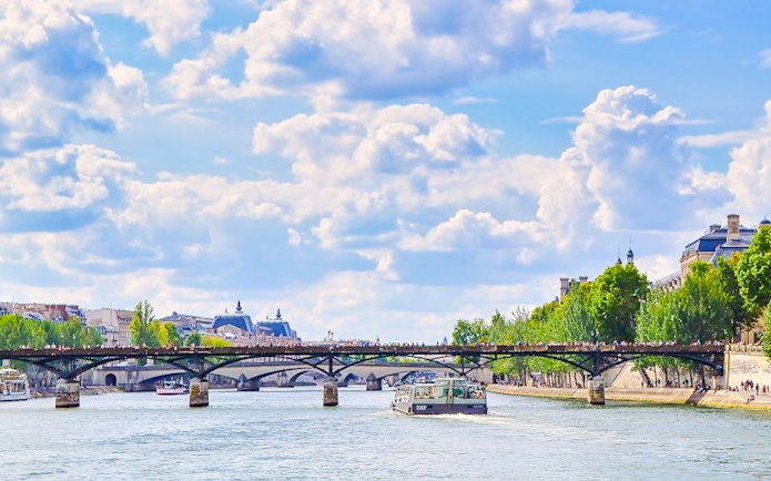 Seine River cruise boat passing under a bridge in Paris.
