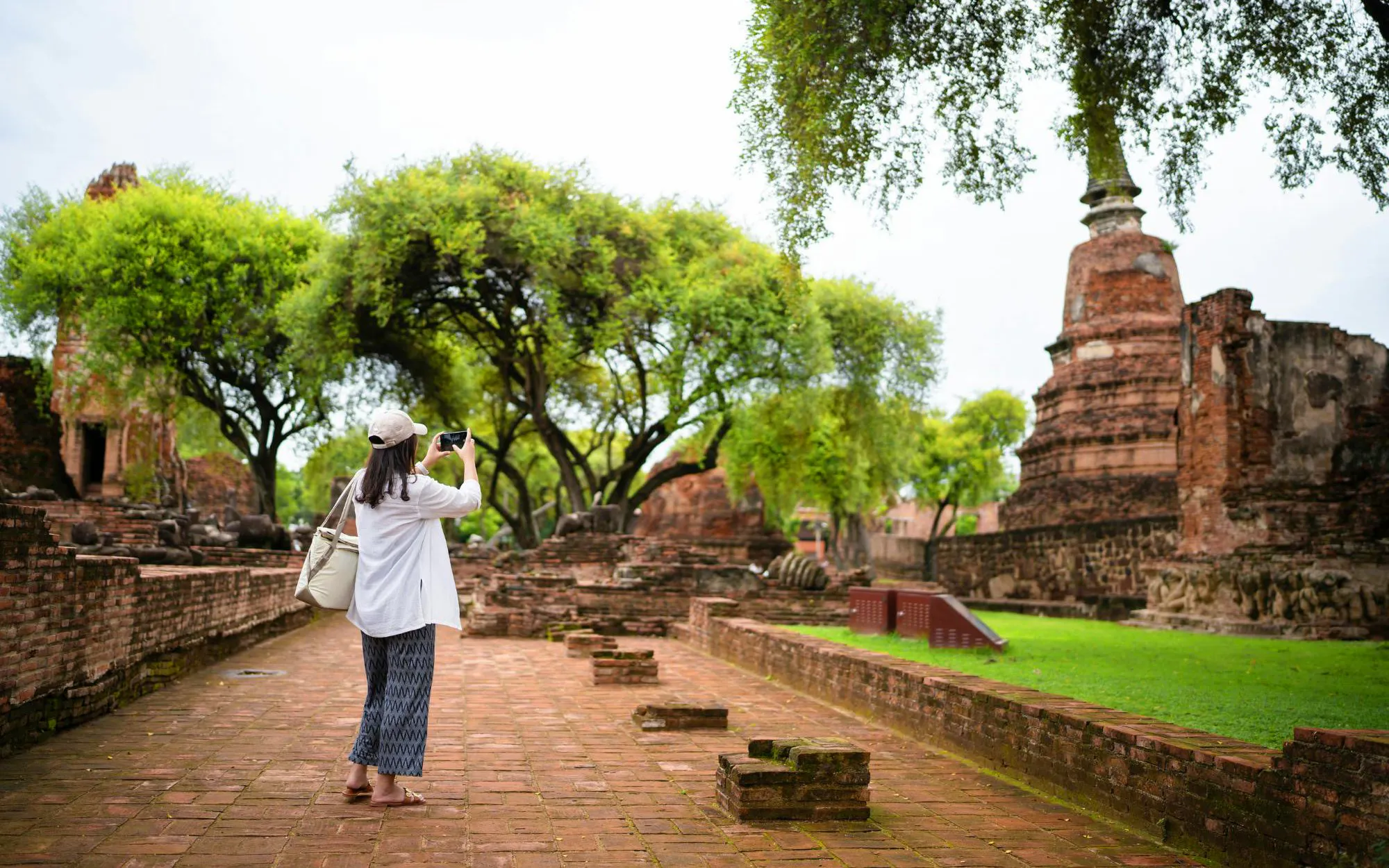 Tourist photographing ancient ruins at Ayutthaya Temples, Thailand.