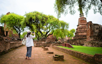 Tourist photographing ancient ruins at Ayutthaya Temples, Thailand.