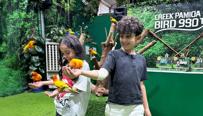 Two children interacting with the birds at Dubai Dolphnairum