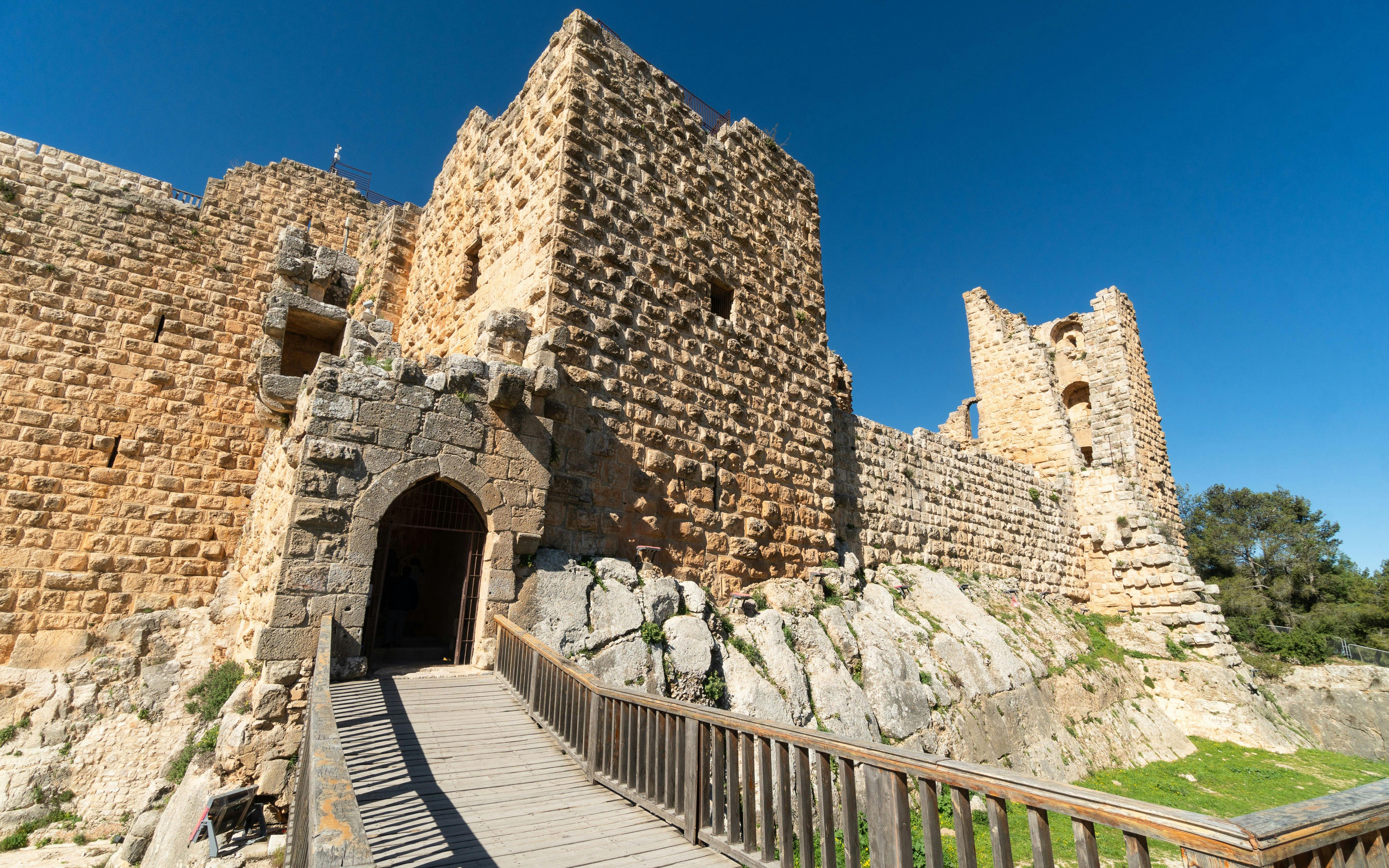 Ajloun Castle stone walls and entrance bridge under clear blue sky in Jordan.