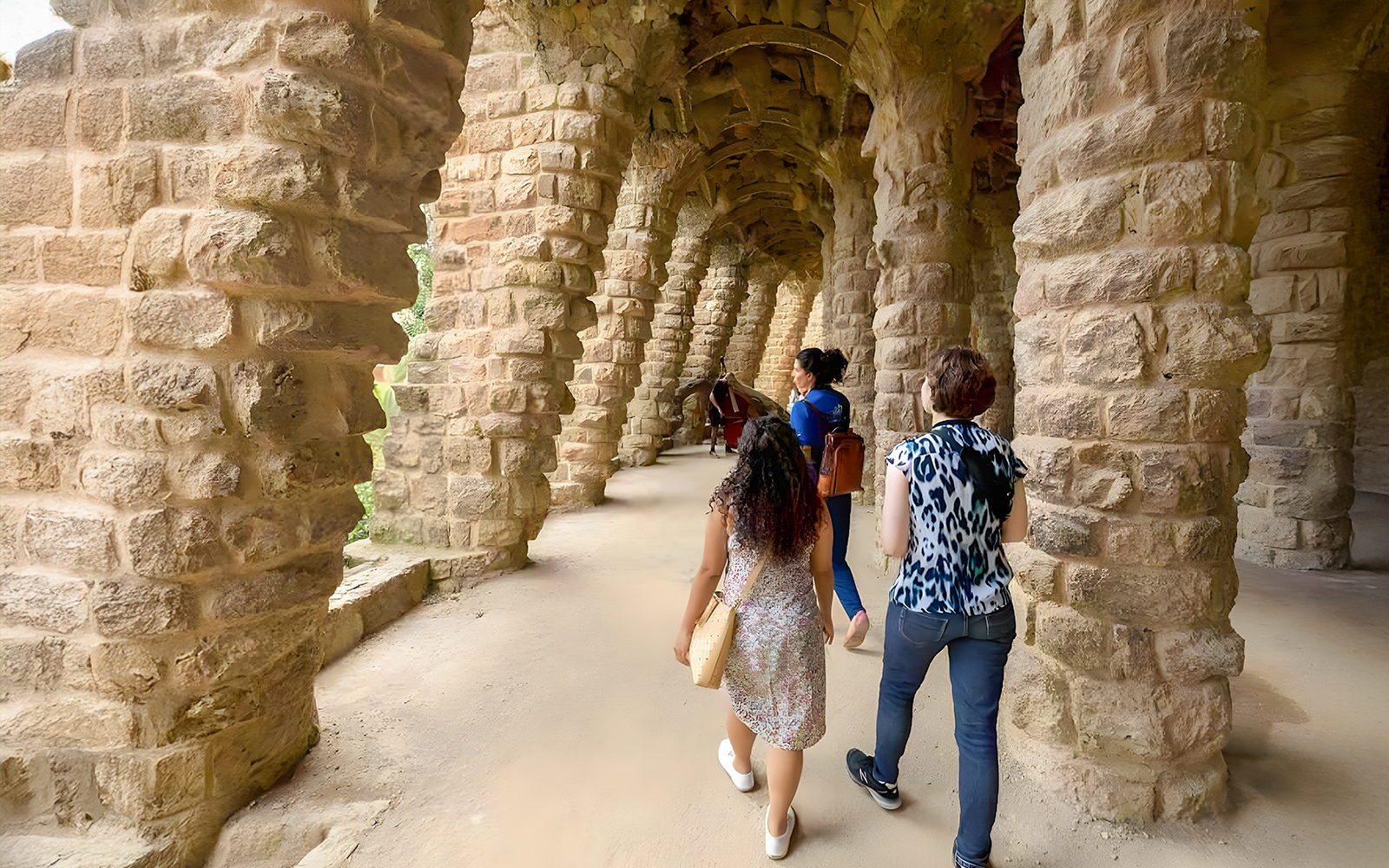 Tourist with guide exploring Park Güell's colorful mosaic structures in Barcelona.