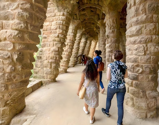 Tourist with guide exploring Park Güell's colorful mosaic structures in Barcelona.