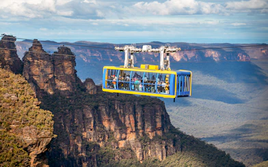 Scenic cable car over Blue Mountains with view of Three Sisters rock formation.