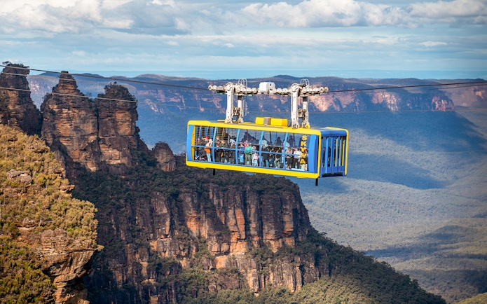 Scenic cable car over Blue Mountains with view of Three Sisters rock formation.
