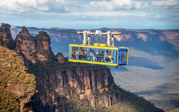 Scenic cable car over Blue Mountains with view of Three Sisters rock formation.