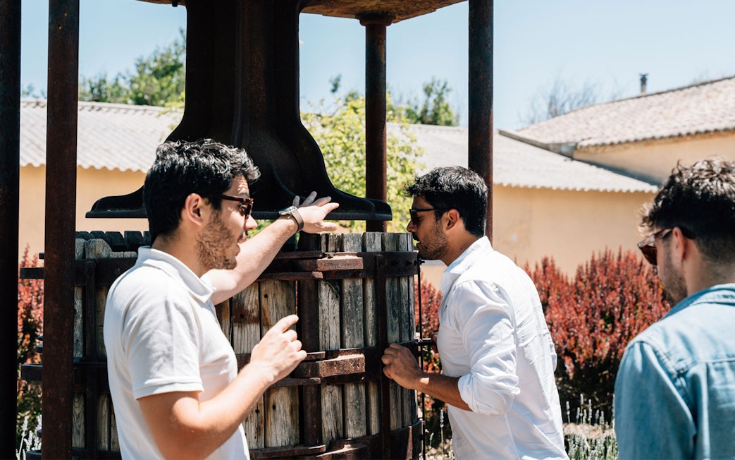 Tourist with guide examining wine press during Toledo winery experience.
