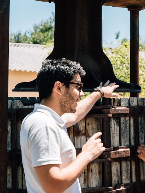 Tourist with guide examining wine press during Toledo winery experience.