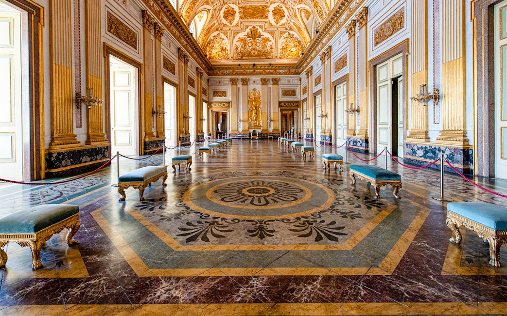 Royal Palace of Caserta interior with ornate ceiling and marble floor.