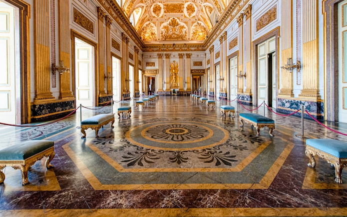 Royal Palace of Caserta interior with ornate ceiling and marble floor.