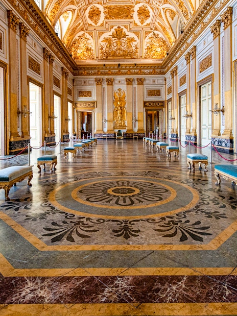 Royal Palace of Caserta interior with ornate ceiling and marble floor.