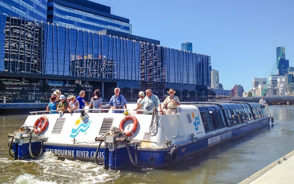 Melbourne River Cruises boat on Yarra River with city skyline in background.