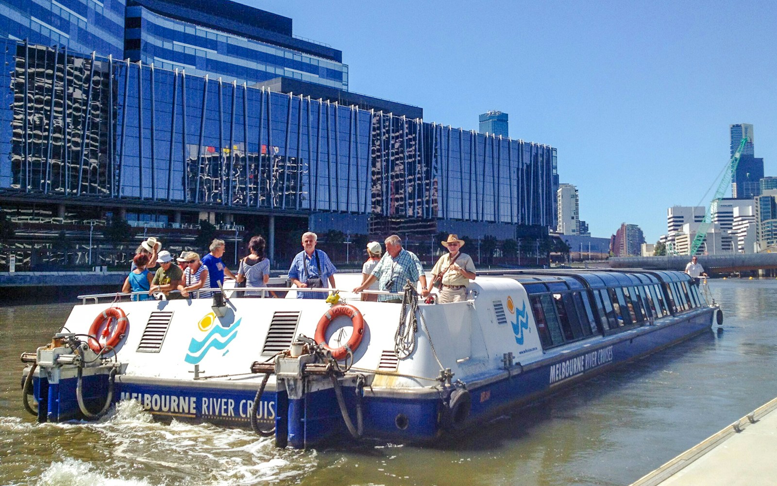 Melbourne River Cruises boat on Yarra River with city skyline in background.