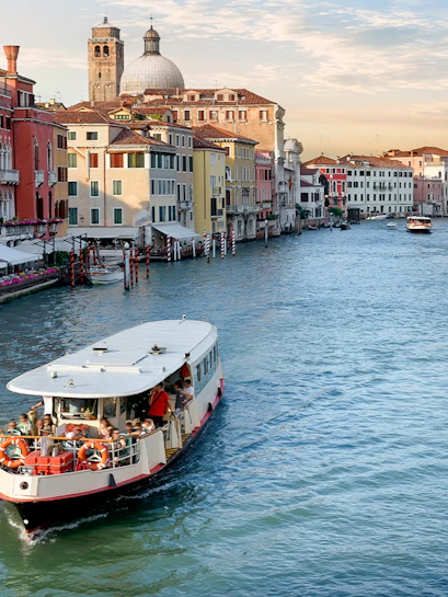 Vaporetto cruising on the Grand Canal in Venice with colorful buildings in the background.