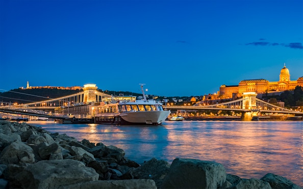 Dinner cruise on the Danube River with Buda Castle and Chain Bridge illuminated at night, Budapest.