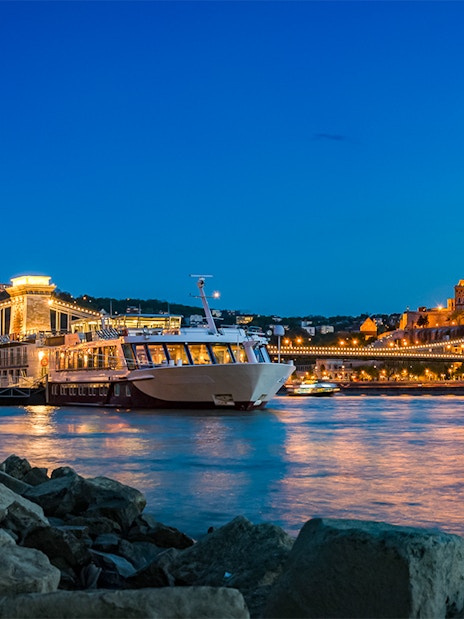 Dinner cruise on the Danube River with Buda Castle and Chain Bridge illuminated at night, Budapest.