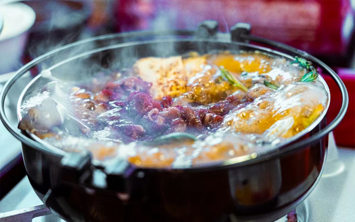 Steaming hot pot with meat and vegetables on a Yakatabune dinner cruise in Japan.