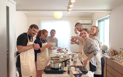 Tourists in Tokyo cooking ramen and gyoza in a class setting.