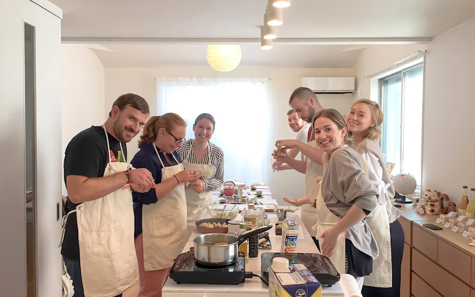 Tourists in Tokyo cooking ramen and gyoza in a class setting.
