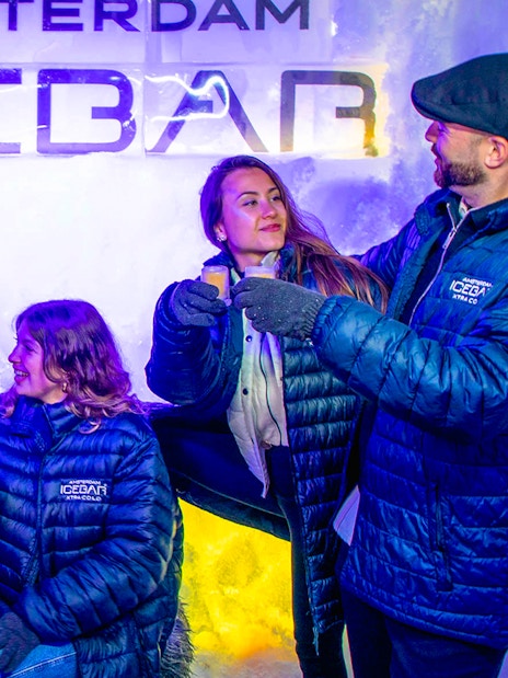 Visitors enjoying drinks at Icebar Amsterdam in winter coats.