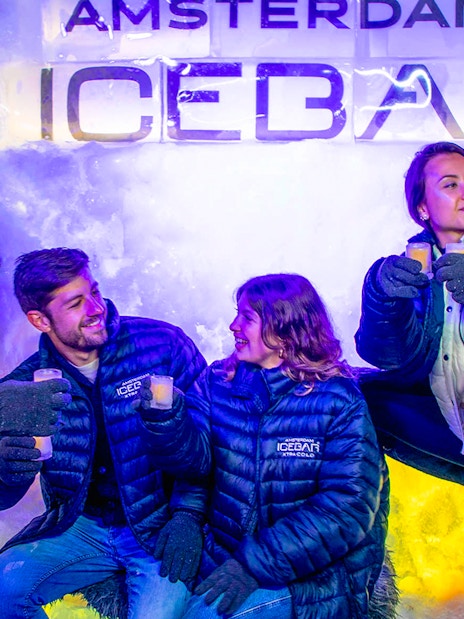 Visitors enjoying drinks at Icebar Amsterdam in winter coats.