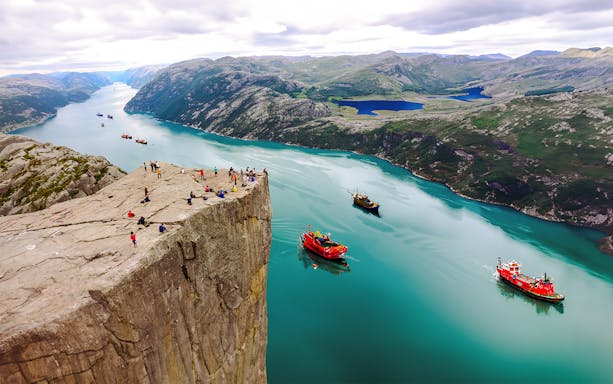 Hikers standing on Preikestolen Cliff overlooking Lysefjord, Norway.